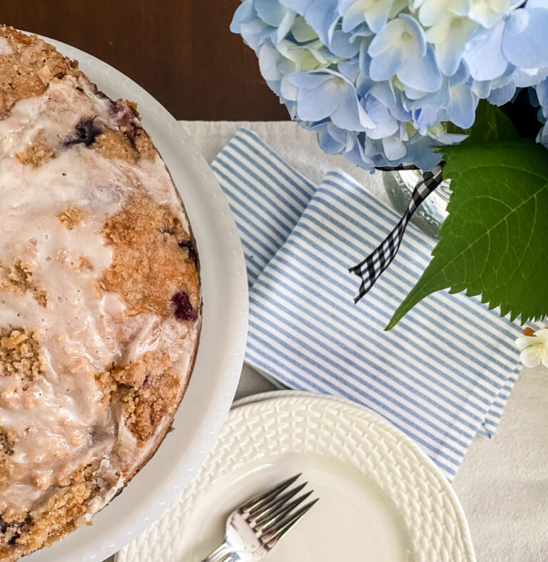 view of blueberry muffin cake with plate, fork, napkins and blue hydrangea