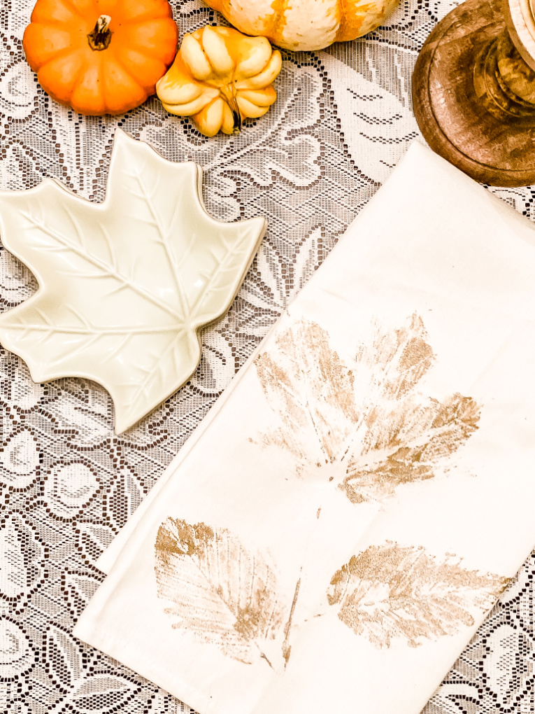 view of leaf stamped tea towel with leaf side plates and pumpkins