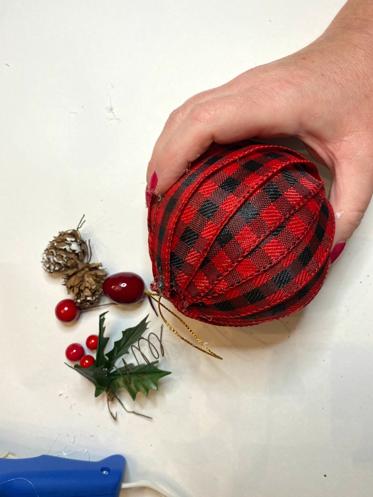Adding Christmas picks to top of diy ribbon wrapped Christmas ornament