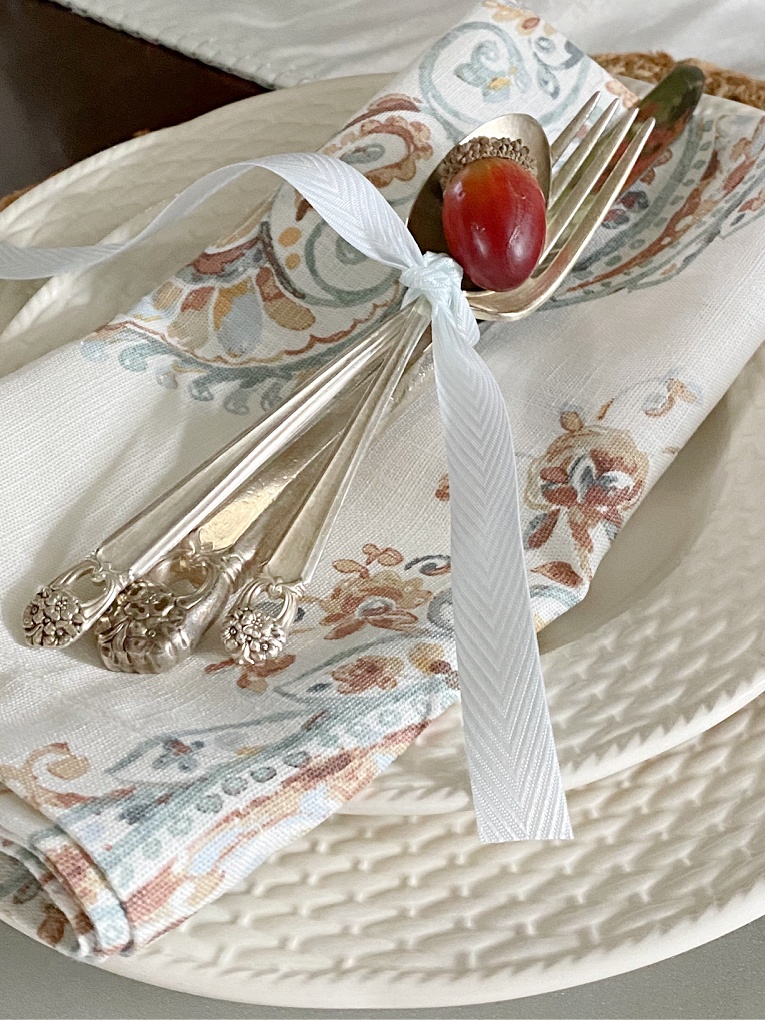 close up of fall napkin and silverware tied with ribbon