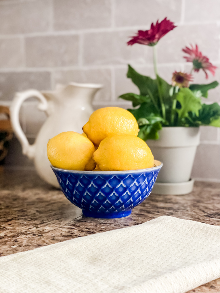 view of lemons in blue bowl and yellow dish towel