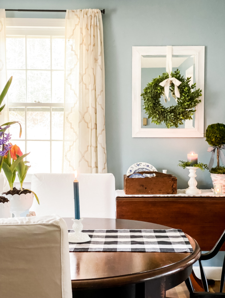 sharing spring decorating ideas with view of dining room table and side table with mirror and topiary