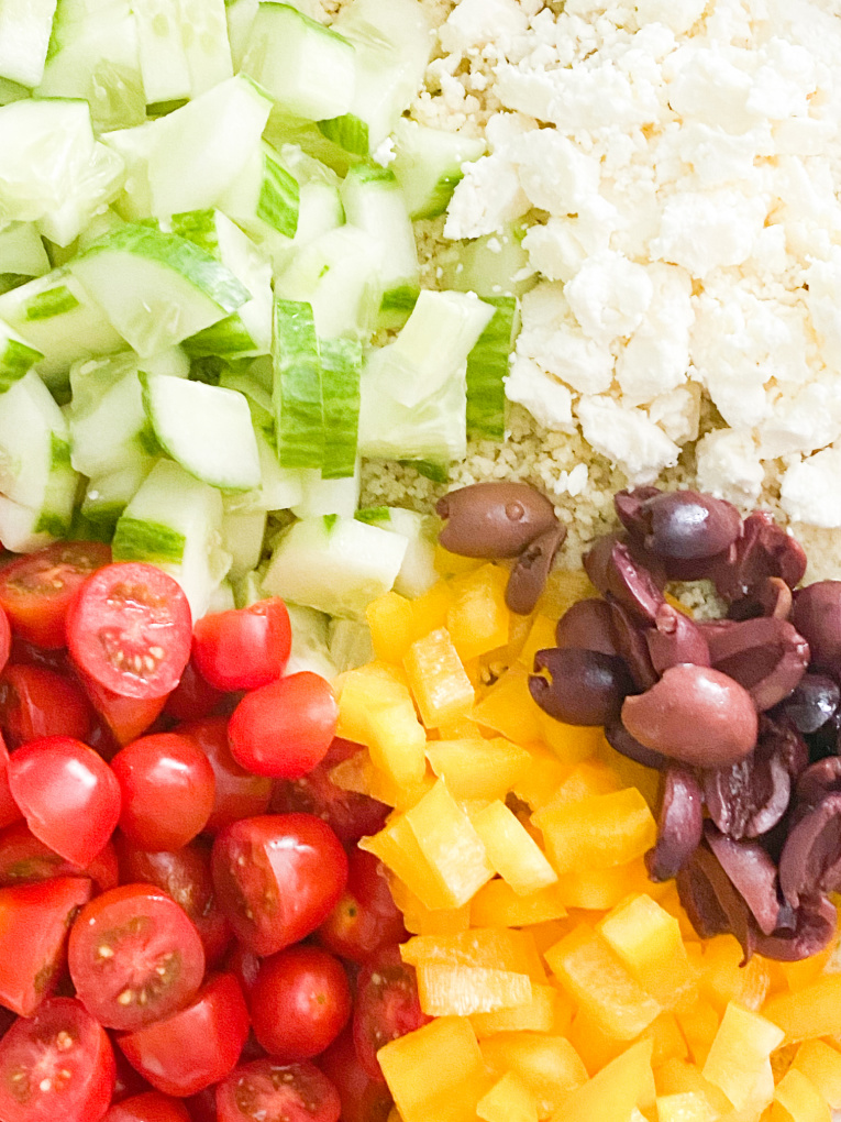 mediterranean couscous salad ingredients: cucumber, tomatoes, yellow peppers, kalamata olives, and feta cheese.