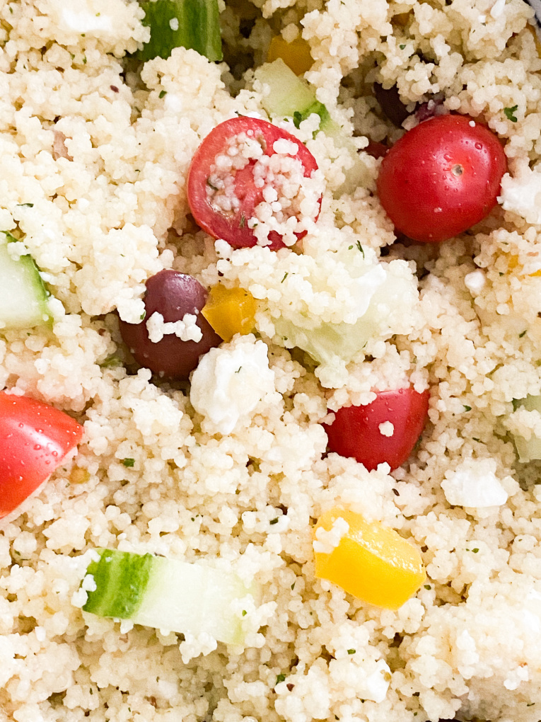 close up of mediterranean couscous salad with cucumber, tomatoes, yellow peppers, kalamata olives, and feta cheese.