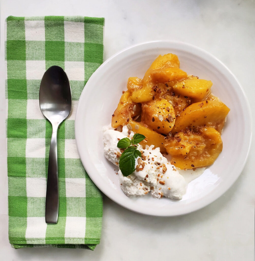 gluten free crockpot peaches in bowl with ice cream, mint, and green and white napkin