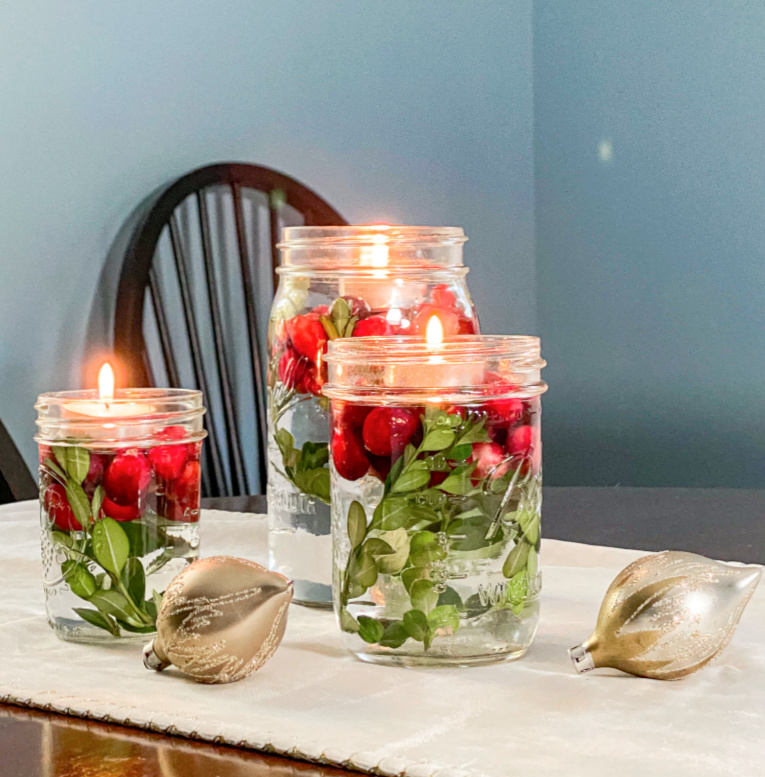 3 DIY Holiday Jar Floating Candles with Boxwood and Cranberries on runner with gold vintage ornaments