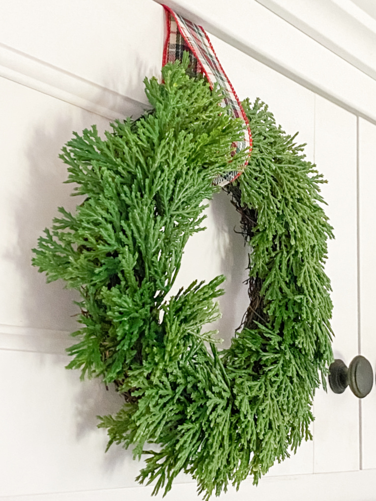 close up of artificial wreath on white cabinet door