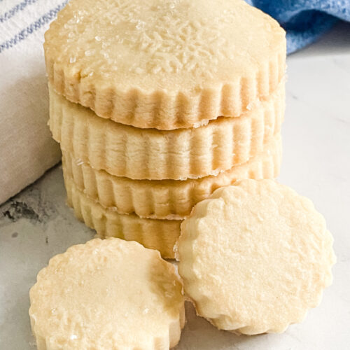 stack of round shortbread cookies with blue and white towels in background.