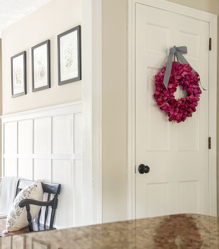 view into hallways with diy board and batten and fuchsia tulip wreath on the door