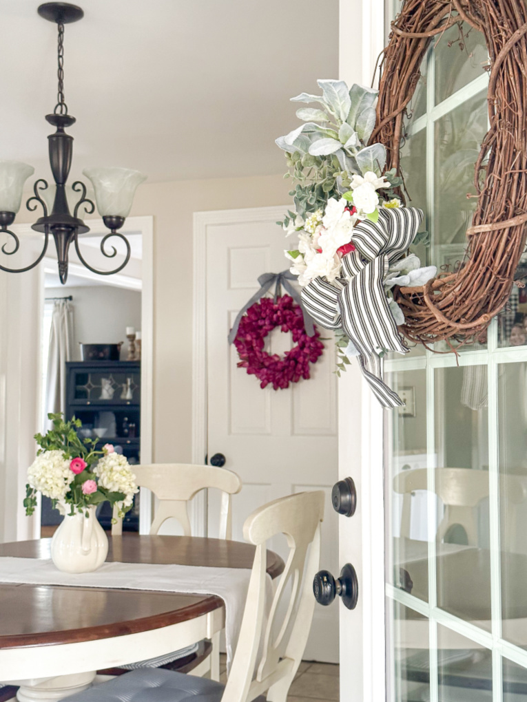 open back door leading into kitchen with fuchsia tulip wreath hanging on white door.