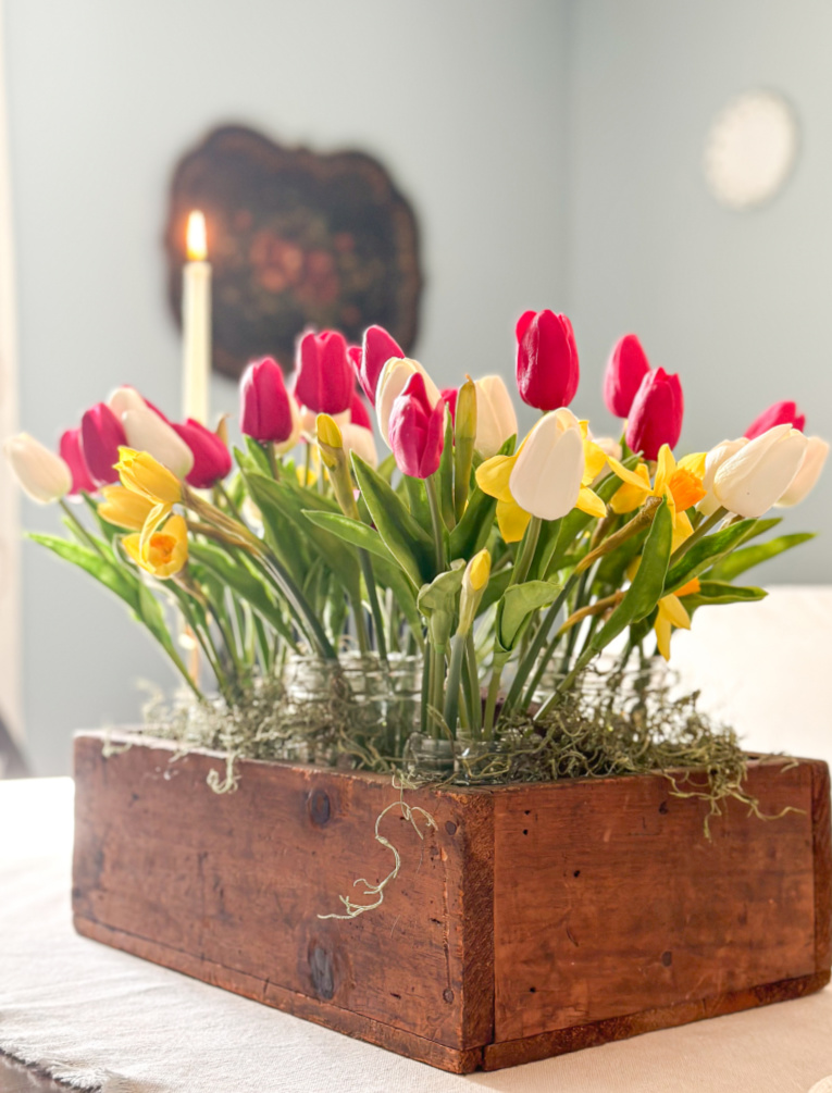 spring centerpiece made of artificial tulips and daffodils on dining room table