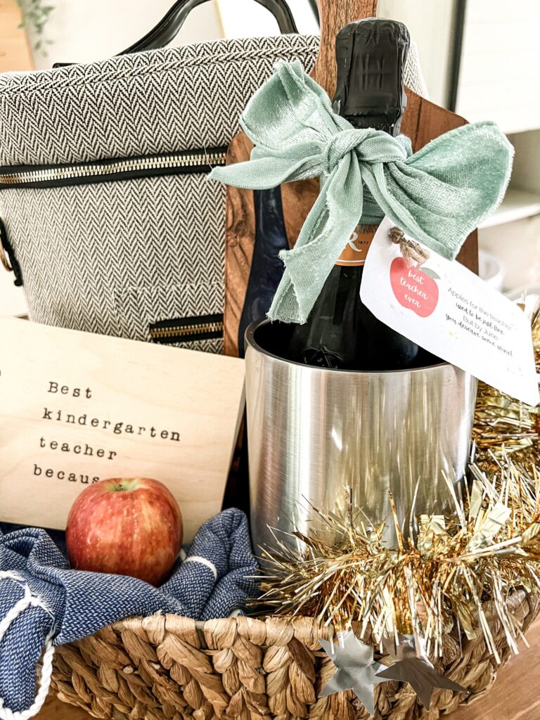 teacher gift basket with wine bottle in chiller, bag, apple and best kindergarten teacher book.