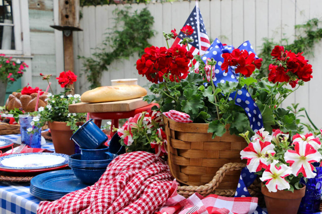 Memorial Day tablescape decorated in red, white and blue with basket of red geraniums