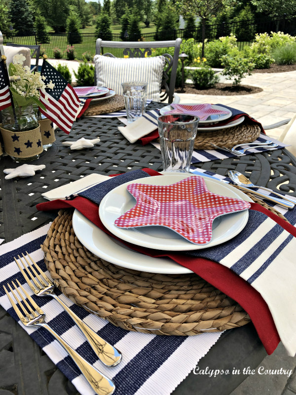 4th of July outdoor table setting with white plates and red start plates