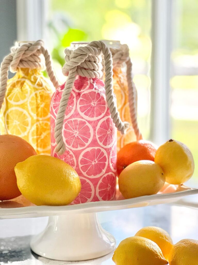 yellow and pink decoupaged glass bottles surrounded by lemons