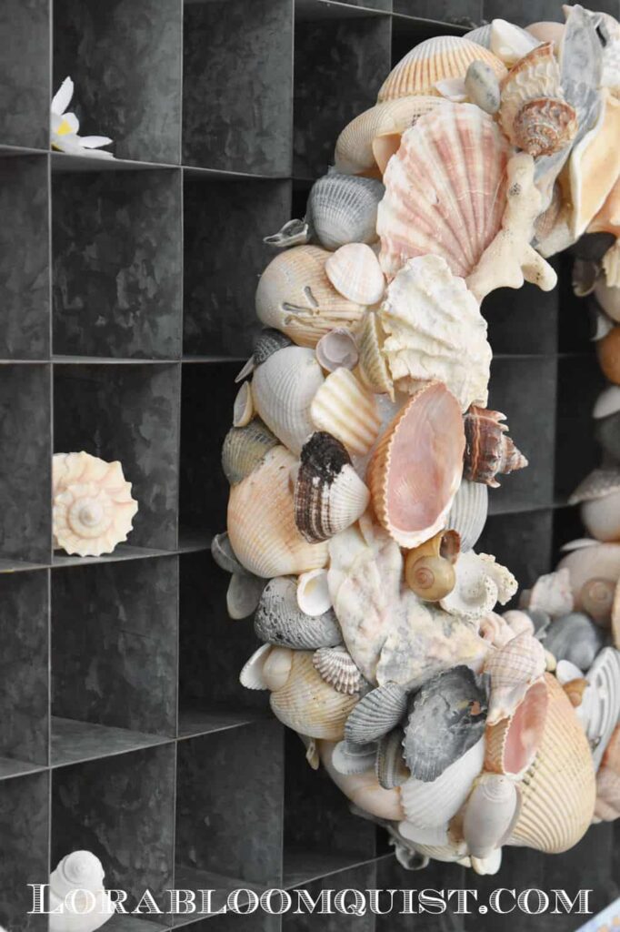 diy shell wreath hanging in front of gray shelf with cubbies