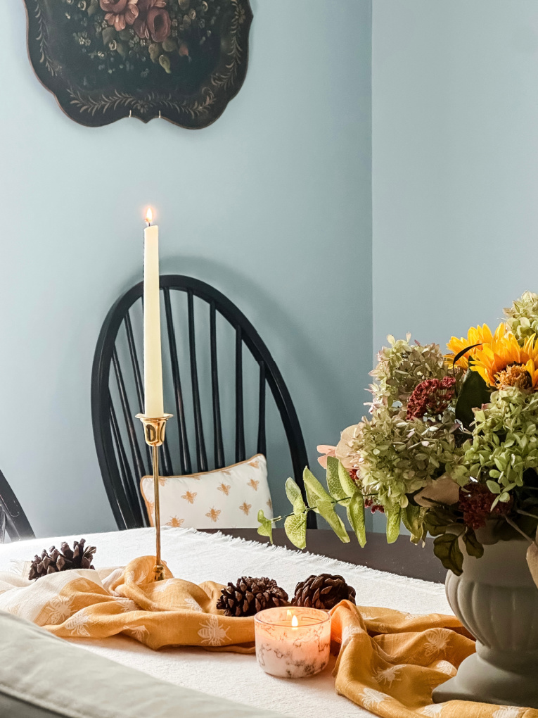 early fall decorating traditional dining room table with yellow accents, brass candlesticks. Vintage black floral tray hanging on blue painted wall.
