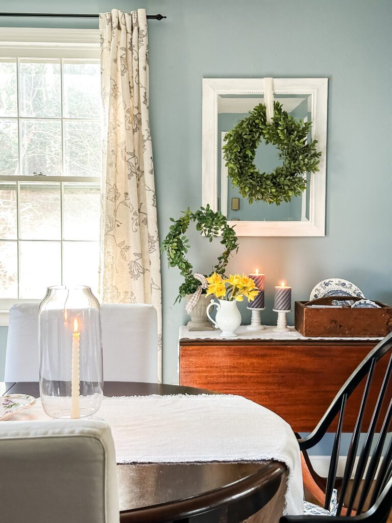 view of side table and mirror with wreath in blue dining room