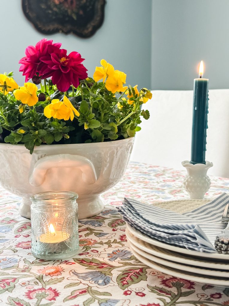 soup tureen with red dahlia and yellow pansies on a dining room table