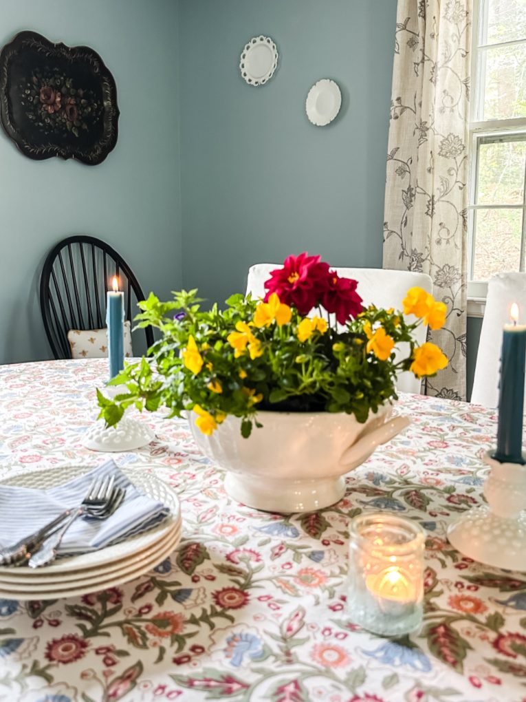 soup tureen with red dahlia and yellow pansies on a dining room table