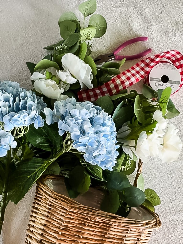 blue hydrangeas, white ranunculus, eucalyptus stems, and wall basket